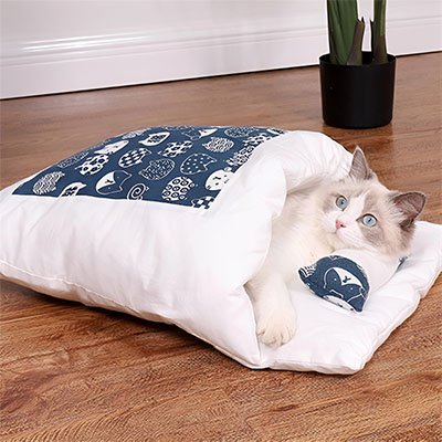 Lit chat en forme de vrai petit lit bleu et blanc avec chat couche dedans de cote